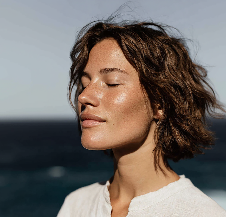 Femme qui ferme les yeux avec mer en arrière plan